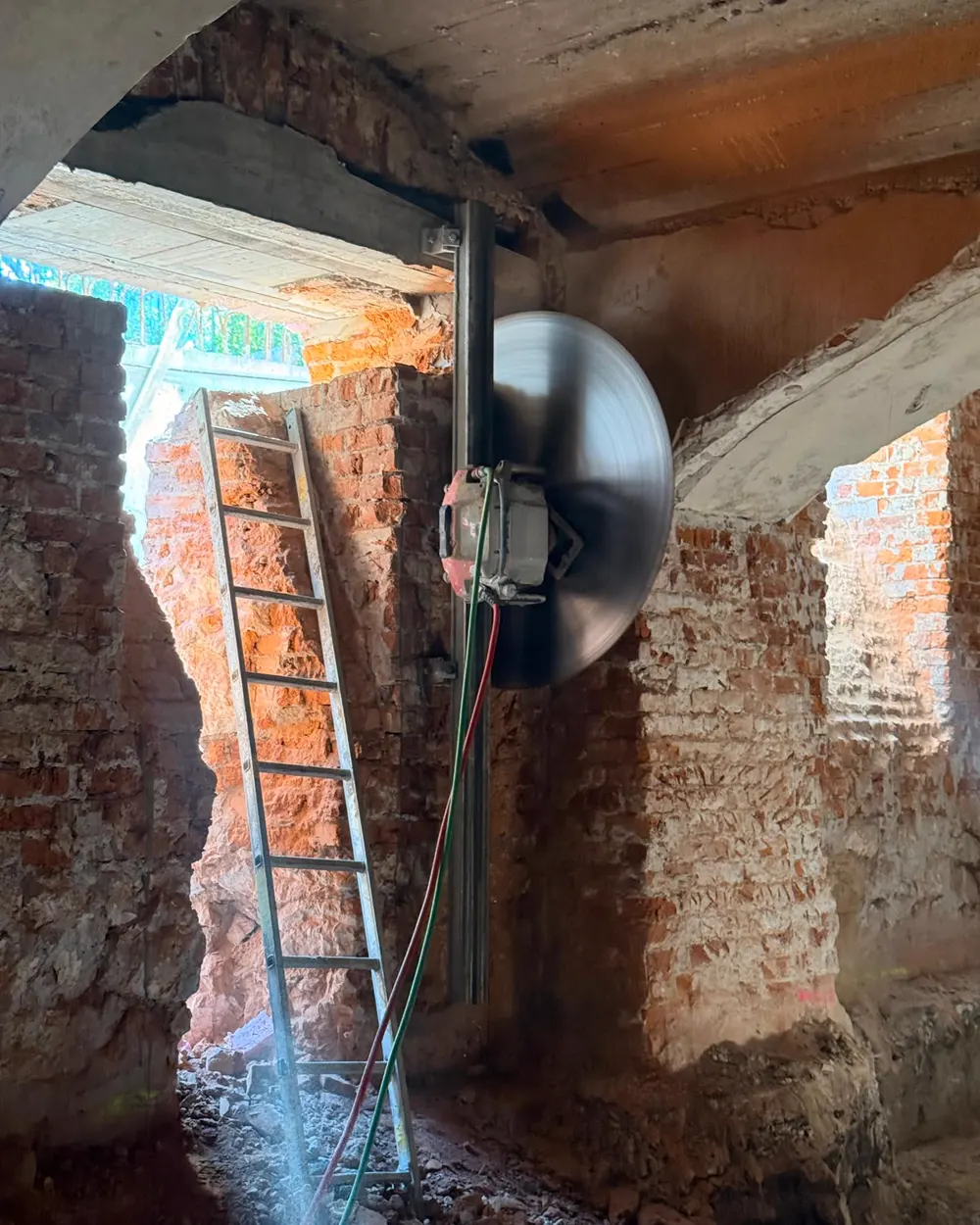 Piła ścienna z tarczą diamentową zamontowana na kolumnie w ceglanej piwnicy ze sklepieniami kolebkowymi
