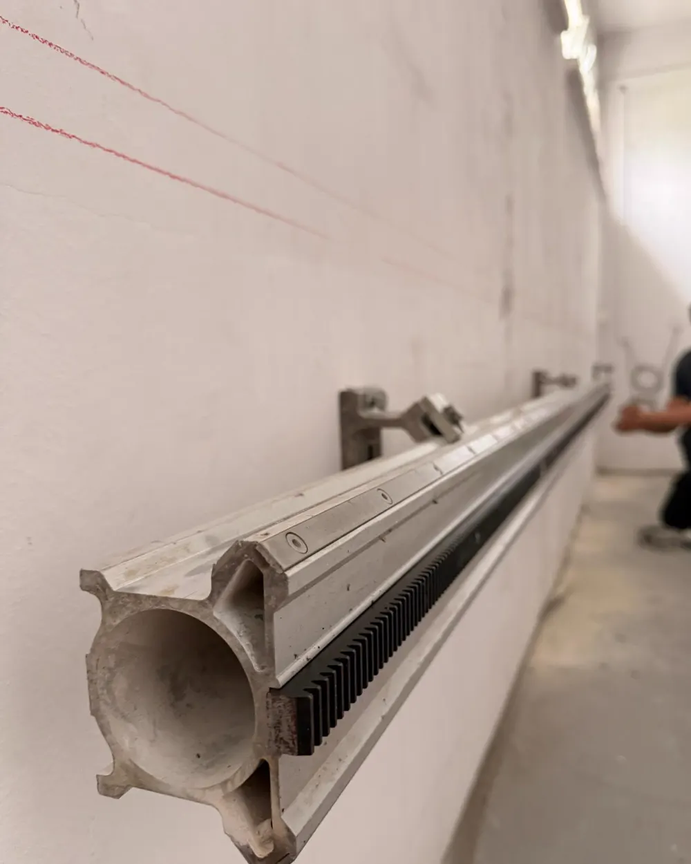 Aluminiowa szyna prowadząca piły ściennej zamontowana na ścianie wzdłuż wytrasowanej czerwonej linii cięcia
