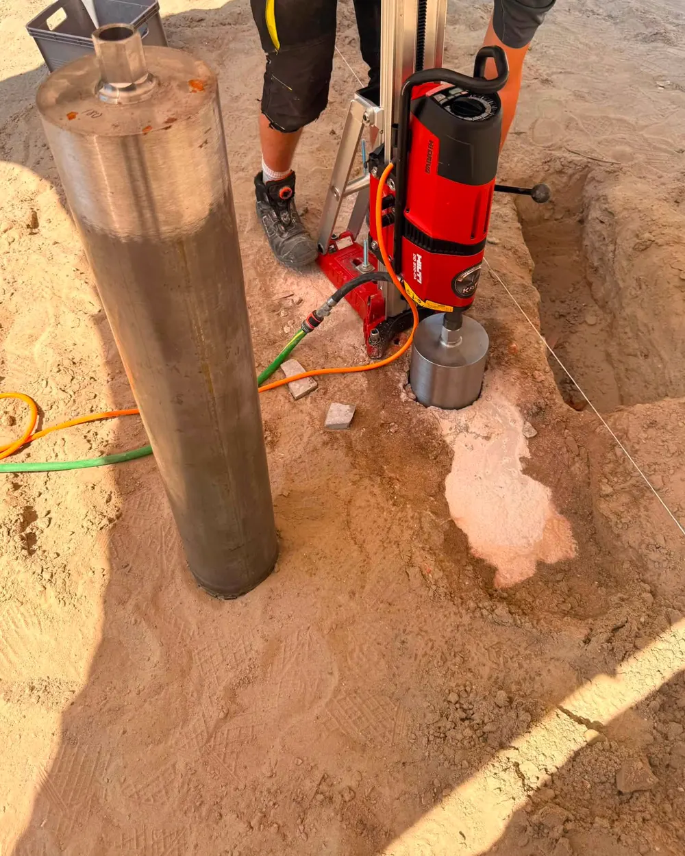 Wydobyty rdzeń betonowy obok wiertnicy Hilti DD 350-CA w wykopie przy zabytkowym murze